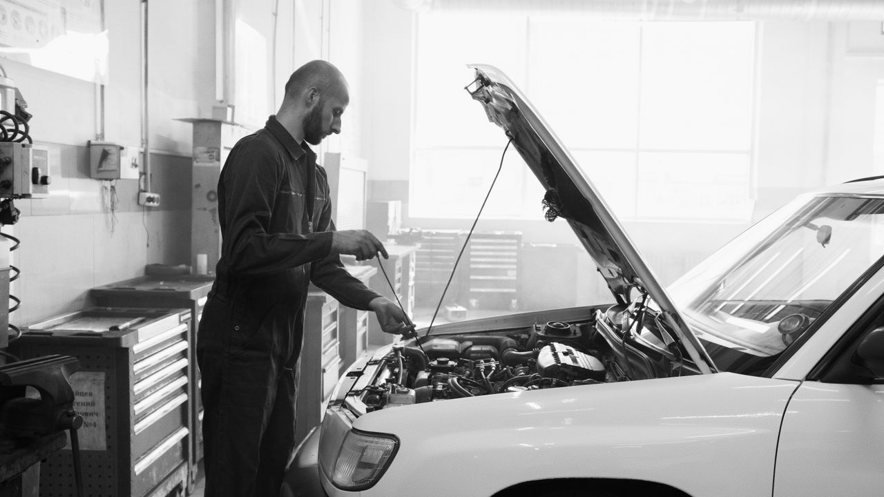 about-img Mechanic in a garage performing engine maintenance on a vehicle.